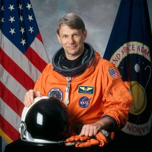 Official NASA portrait of Piers Sellers in his orange astronaut suit.